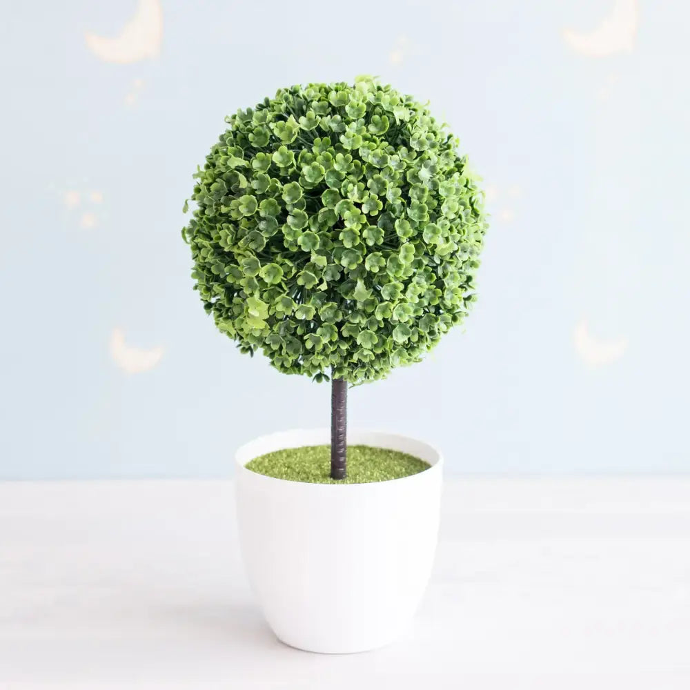 A lush artificial bonsai tree with green foliage and pink accents in a white ceramic pot for garden decor