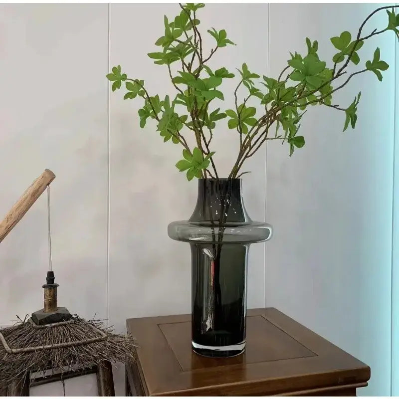 A sleek dark gray artisan glass vase with a modern tiered design on a wooden table for elegant decor