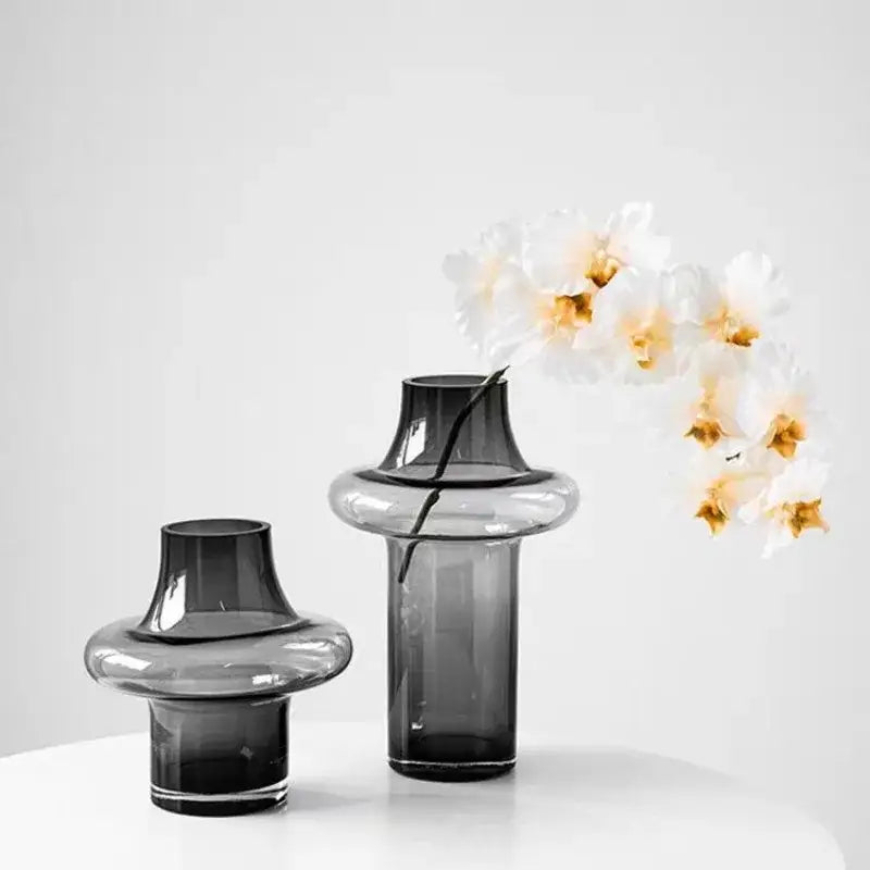 Two sleek dark gray artisan glass vases with modern tiered designs for elegant home decor on a white surface