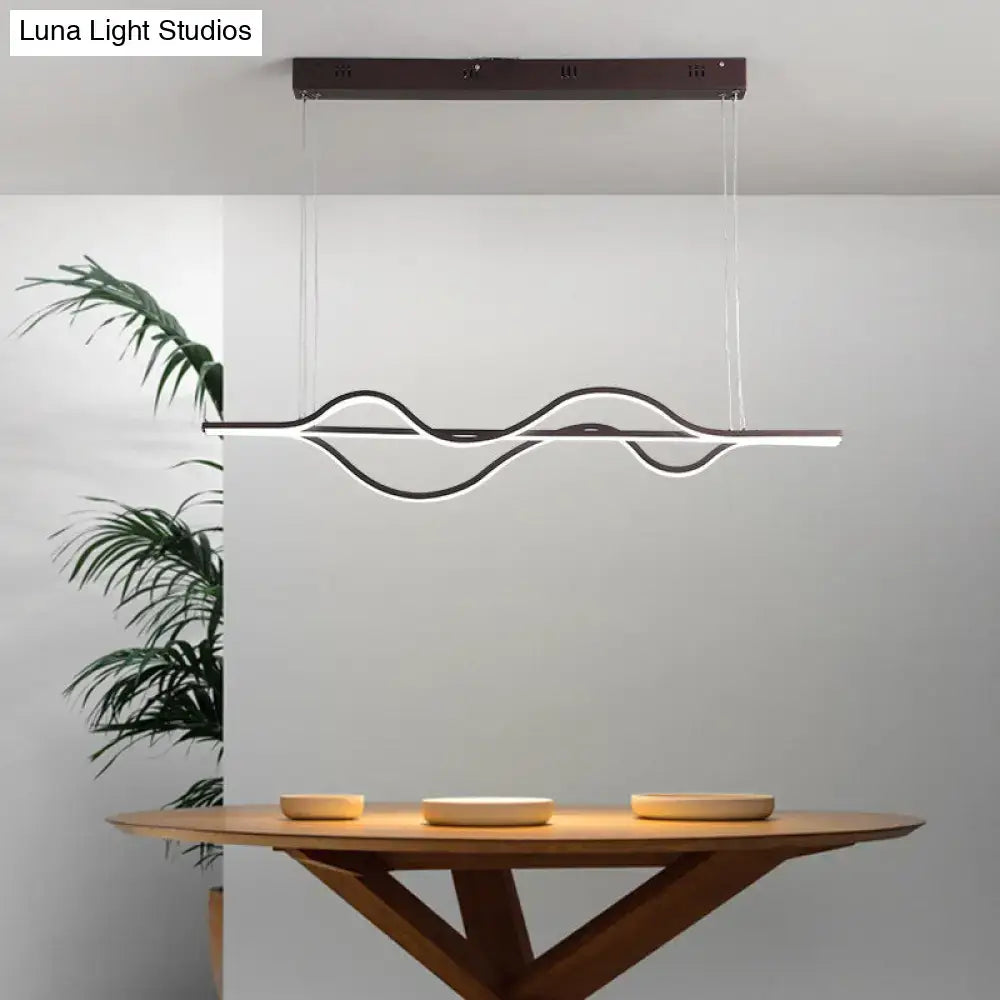 Modern black and white artistic metal dining pendant light fixture with wavy design hanging above wooden table