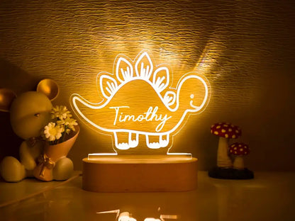 A glowing personalized dinosaur-shaped led night light with the name timothy in white cursive for baby kids decor
