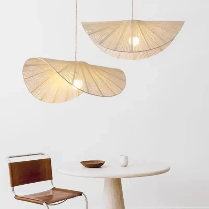 Two bamboo wabi sabi woven rattan pendant lights in warm beige with natural texture hang above minimalist dining table