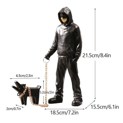 Black glossy banksy dog walker resin statue holding a gold chain leash attached to a small dog accessory