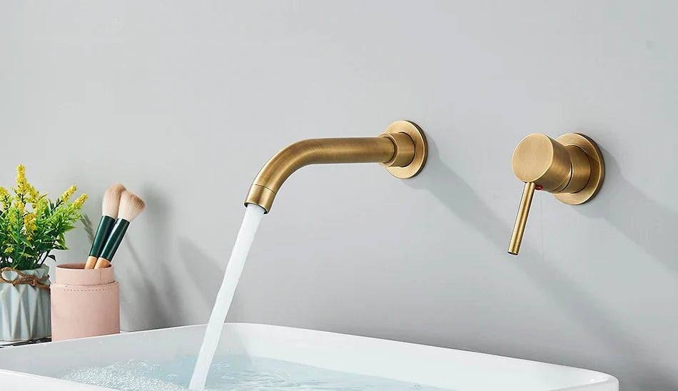 Gold-toned basin faucet wall mounted bathroom fixture with brushed brass finish and hot water control handle