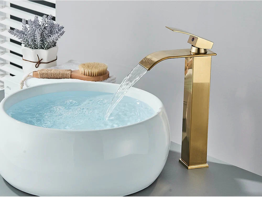 Gold-toned bathroom sink faucet brass deck mount with stainless steel waterfall spout and sleek modern design