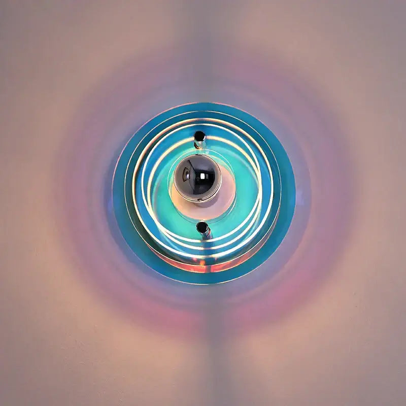A modern bauhaus led wall sconce with blue and white glass rings and a reflective black sphere for bedroom or living room
