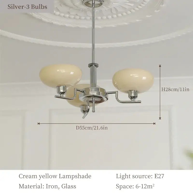 A bauhaus medieval chandelier with three cream yellow glass lampshades and a polished chrome iron frame for living rooms