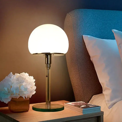 A bauhaus mushroom table lamp with a frosted white glass shade and brass-finished metal base for bedroom use