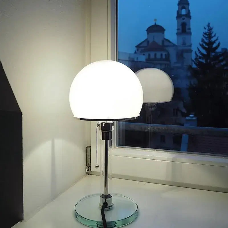 A bauhaus mushroom table lamp with frosted milk white glass shade and chrome metal base for bedroom lighting