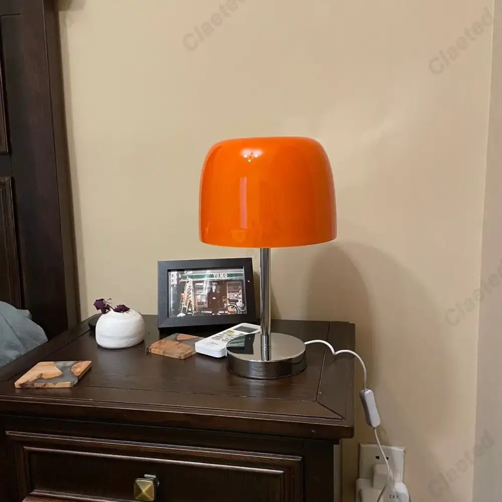 Vibrant orange glossy glass bauhaus retro table lamp with sleek chrome base perfect for bedroom use