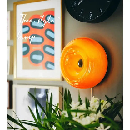 Vibrant bauhaus orange glass wall lamp with a glossy circular design perfect for modern bedroom accessories