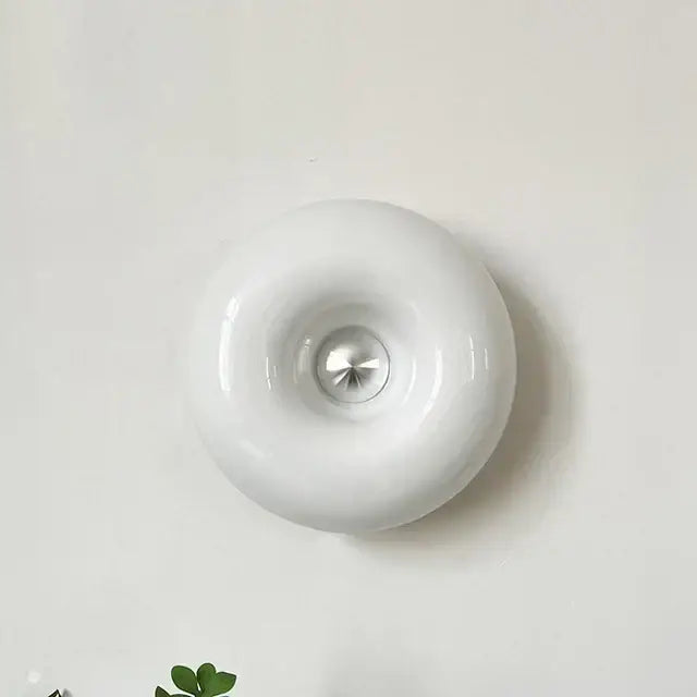 White glossy ceramic wall sconce with central metallic accent complements bauhaus orange glass bedroom accessory