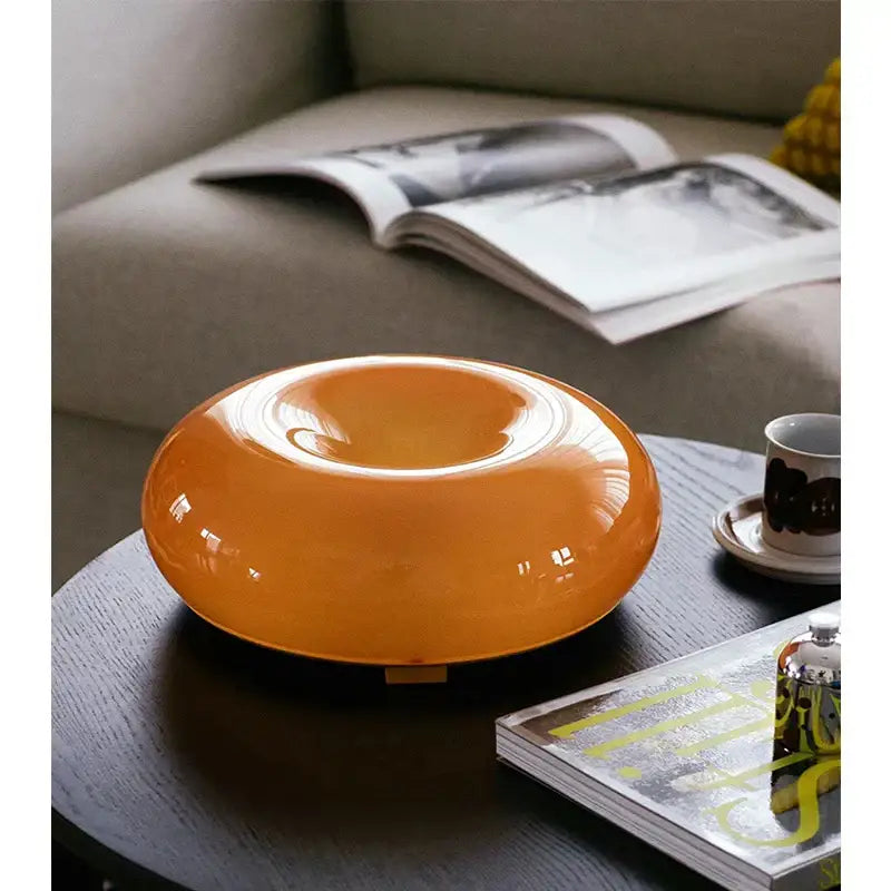Glossy bauhaus orange glass table lamp with translucent donut shape and smooth rounded design for bedroom desk use