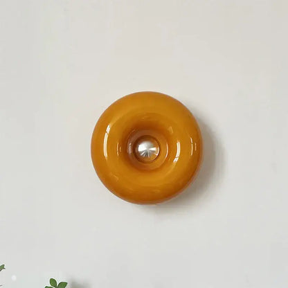Bauhaus orange glass table lamp featuring a glossy amber glass wall sconce with central metallic accent for bedroom use