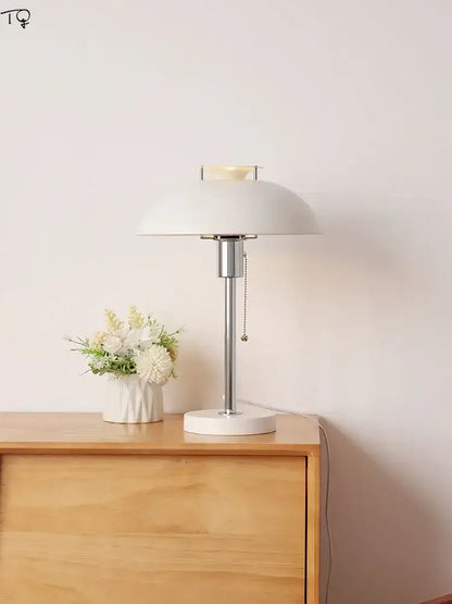 A sleek white ceramic bauhaus led table lamp with polished chrome stem and minimalist dome shade for bedrooms