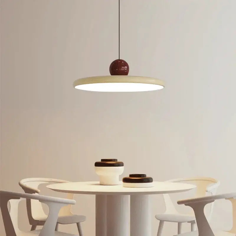 Minimalist bauhaus saucer chandelier with matte cream circular shade and glossy burgundy spherical top for dining room