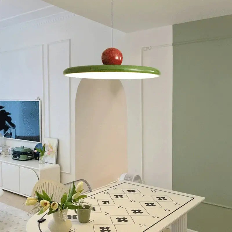 A modern bauhaus saucer chandelier pendant light with a vibrant green circular shade and glossy red top for dining rooms