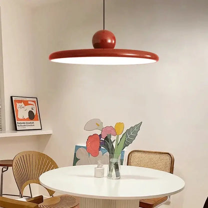 A sleek modern red bauhaus saucer chandelier pendant light with circular shade and glossy spherical top for dining room