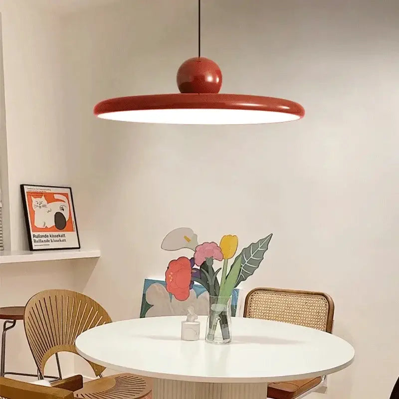 A sleek modern red bauhaus saucer chandelier pendant light with circular shade and glossy spherical top for dining room