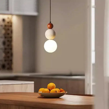 A pendant light with stacked wooden, travertine stone, and glass spheres works beautifully in a dining room setting