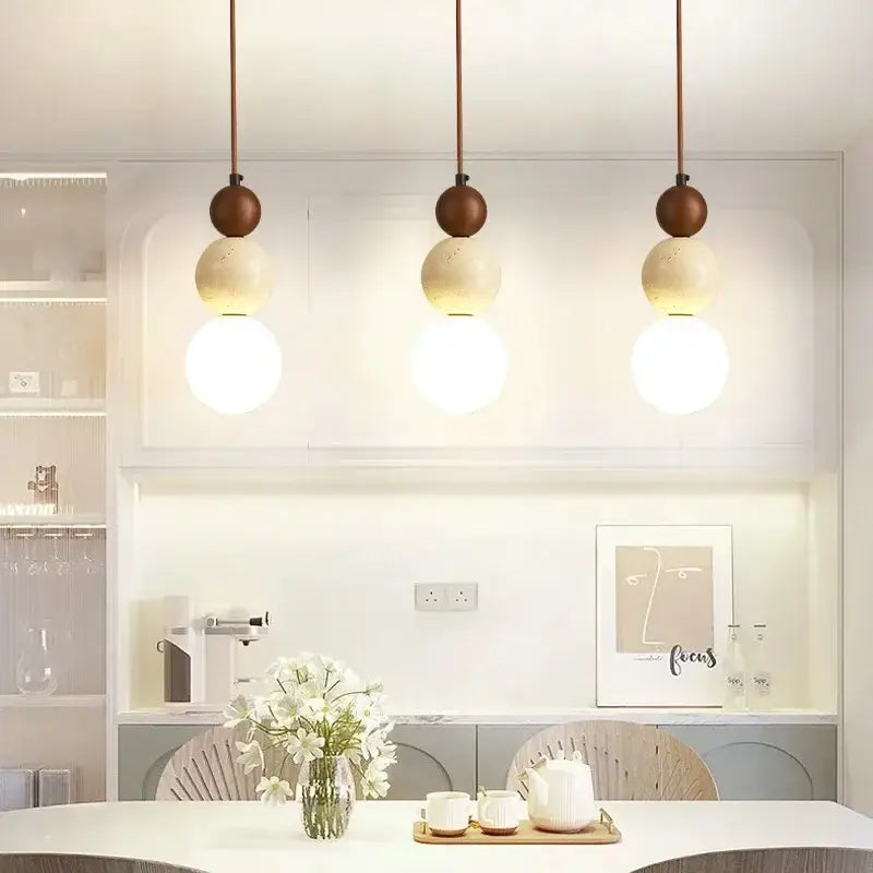 Three modern cord pendant lights with matte brown wooden spheres and warm led bulb glass for dining room use