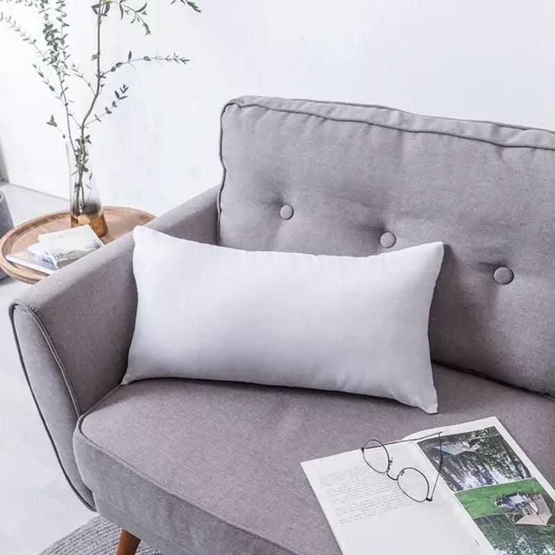 A sleek white cushion cover with decorbites geometric embroidery tassel detail on a gray sofa for living room decor
