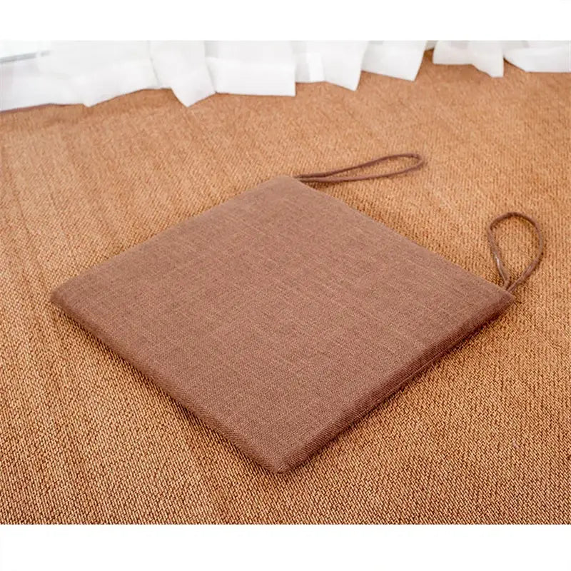 Beige and brown decorbites linen seat cushion with textured fabric and two woven handles for dining room chairs