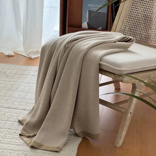Beige and cream herringbone knit throw blanket draped over wooden chair decorbites cozy striped living room throw