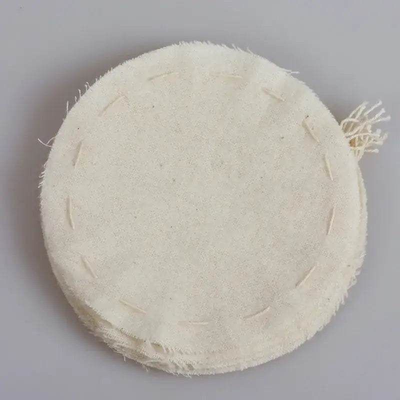 Beige eco-friendly flannel cloth coffee filter with off-white circular shape, frayed edges, and visible stitching in kitchen set