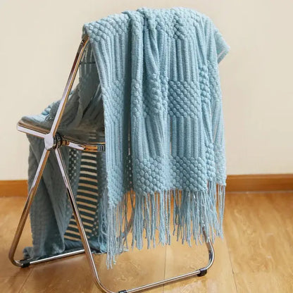A soft light blue decorbites 3d knitted tassel blanket with textured cable bobble pattern and tassels for bedroom decor
