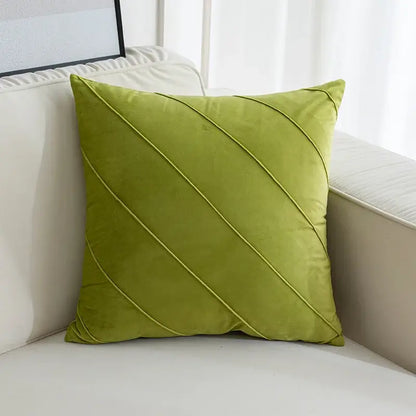 Olive green velvet square pillow with diagonal quilted lines featured among hand pleat embroidered cushions