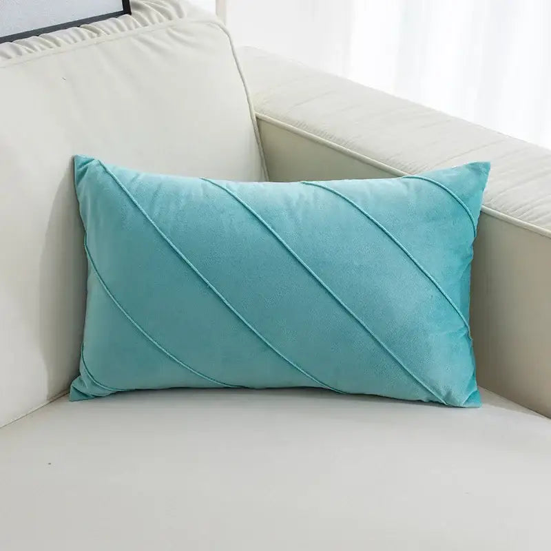 A soft teal velvet rectangular pillow with hand pleat embroidered diagonal stitched pleats for living room use