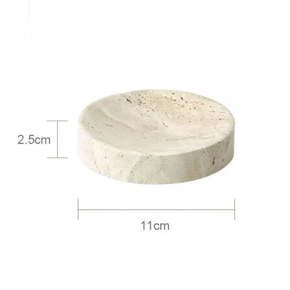 A round off-white stone soap dish with speckled texture and raised rim from the decorbites beige travertine marble set
