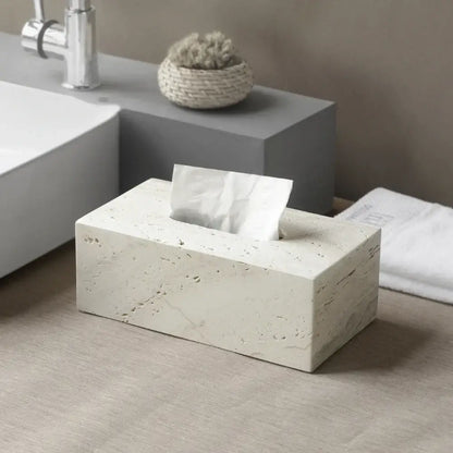 A beige travertine marble rectangular tissue box with textured stone surface and white tissue partially pulled out