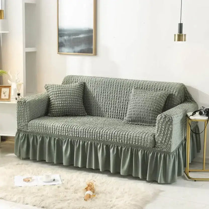 A sage green waffle-textured cozy sofa cover with ruffled hem ideal as a cozy sofa slipcover