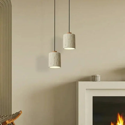 Two beige wood grain columnar micro cement pendant lights with textured ceramic finish and dark metal cords for decorbites decor