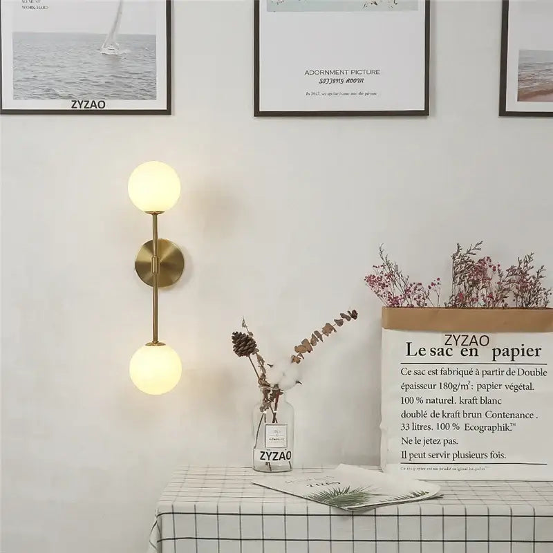 Gold-toned wall lamp with dual spherical glass shades for bedroom decorbites golden glass led sconce design