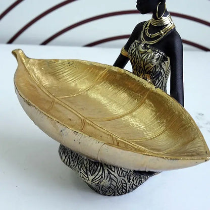 Black woman resin figurine in black and gold holding a large golden leaf tray for living room decorbites decor