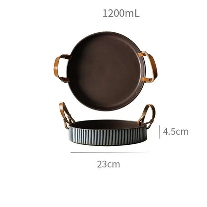 Dark brown ceramic serving tray with gold toned handles and striped rim paired with decorbites porcelain bowl with leather handle