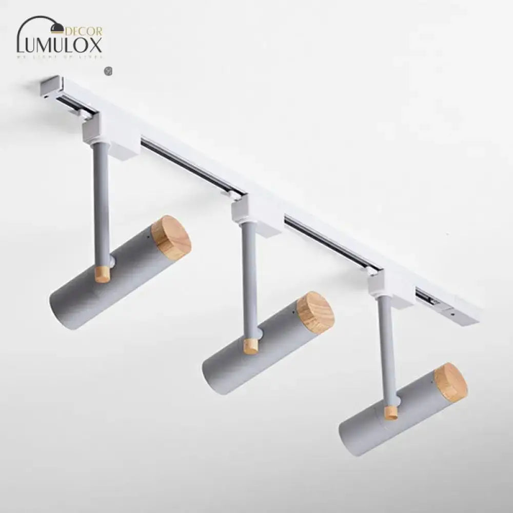 Modern gray cylindrical track lights with natural wood caps mounted on sleek white rail by decorbites™