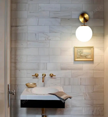 Bathroom sink with gold fixtures illuminated by DecorBites™ black battery operated wall sconces with remote control