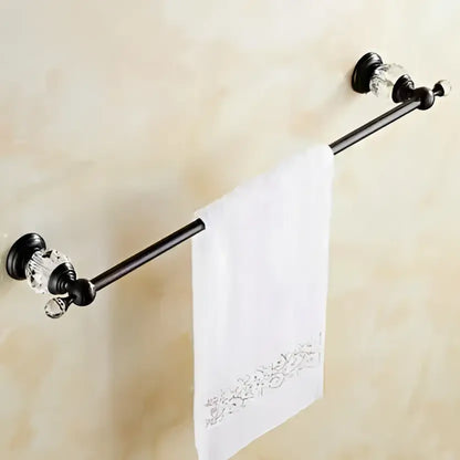 Black brass towel rack with crystal embellishments holding a white embroidered towel in bathroom accessories set