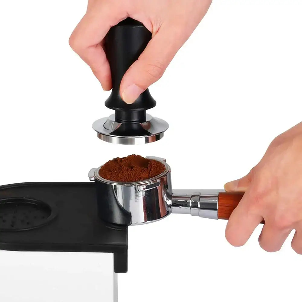 Black calibrated espresso coffee tamper with silver metal base and wooden spring handle pressing coffee grounds
