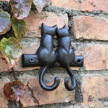 Black cast iron decorbites cat hook shaped like two cats sitting back-to-back on a wooden branch for hanging shelf decor