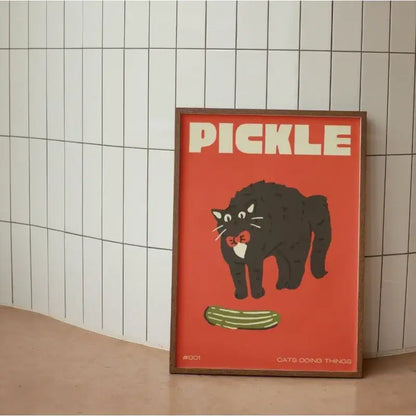 Framed DecorBites™ wall art canvas with a bold red background featuring a funny black cat holding a pickle