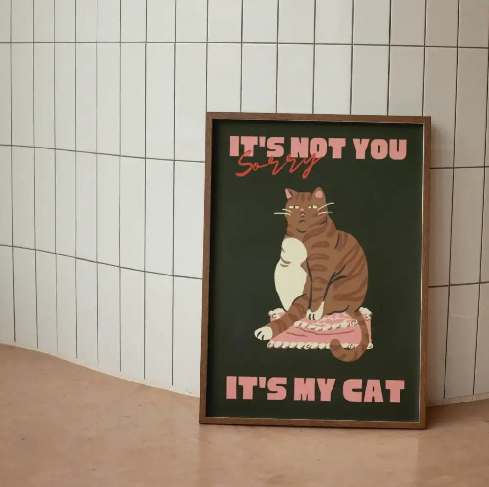 A framed DecorBites™ wall art canvas featuring a funny brown tabby cat on a pink cushion and dark green background