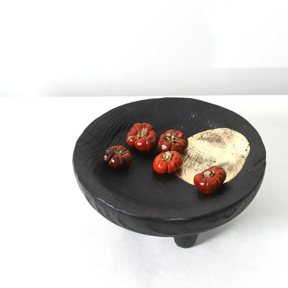Black ceramic corner tray with wood grain texture and gold-toned inlay holding red decorative pumpkins decorbites imitation wood