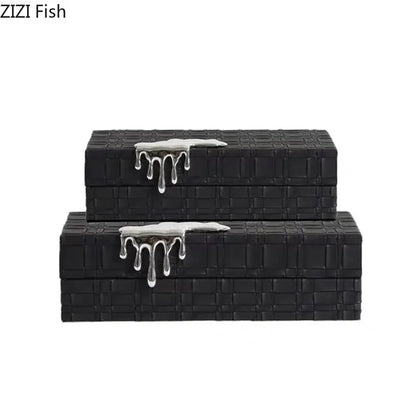 Black rectangular leather jewelry box with textured woven pattern and silver metallic drip accents on lids for storage