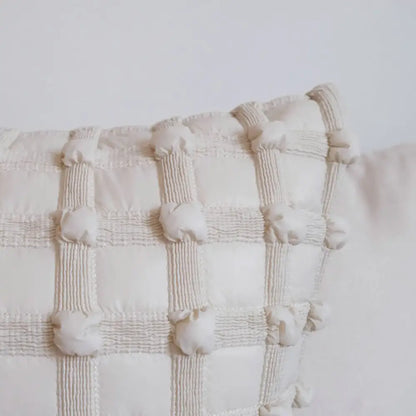 Off-white quilted cushion cover with dot bubble textured grid and pom pom detailing for home decor