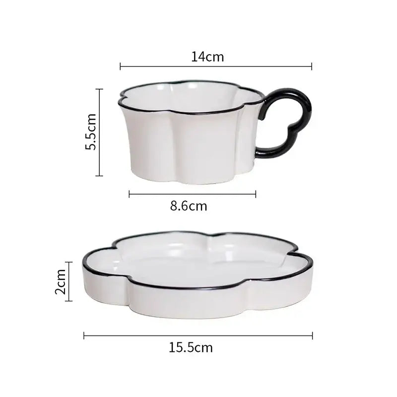 White ceramic mug set with black edged flower design featuring a heart-shaped handle on cup and matching saucer